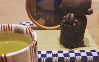 Grüner Tee mit einer Süßigkeit und einer kleinen japanischen Figur - wie kann man schöner Pause machen?!