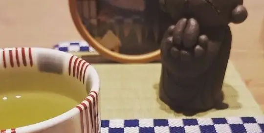 Grüner Tee mit einer Süßigkeit und einer kleinen japanischen Figur - wie kann man schöner Pause machen?!